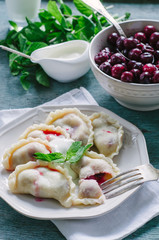Homemade dumplings with cherries and sour cream
