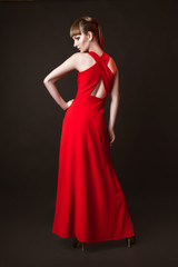 beautiful woman model posing in simple elegant red dress in the studio on black background