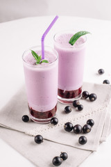 cold milkshake with a black currant on a white background, close-up