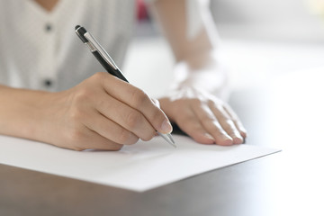 Closeup of woman's hand writing on paper with pen