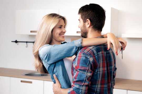 Hugging couple with keys in kitchen