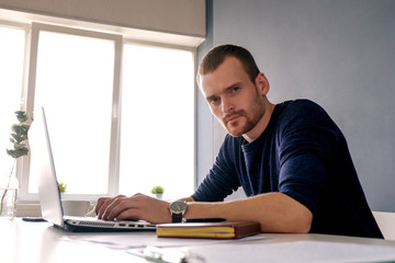Fototapeta premium Serious businessman using laptop and looking at camera
