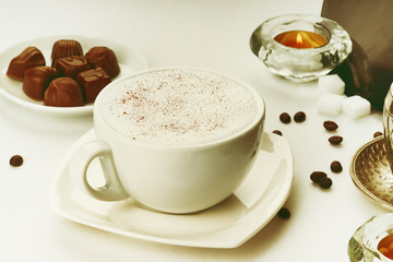 Coffee cup, coffee beans, chocolate candies and candle