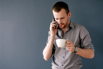 Bearded businessman talking over cell phone with cup in hand