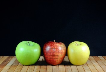 Three apples with apple in the brick wall texture. On teak matting and black background. Copy space.