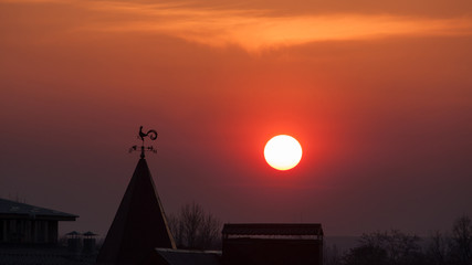 Fototapeta premium Magnificent sunset over the rooftops. wind indicator.sun.