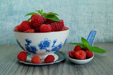 Fresh juicy raspberries in a porcelain dish. Selective focus
