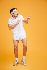 Shocked astonished young sportsman pointing away with both hands