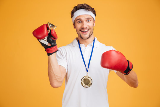 Man boxer in red gloves and medal holding trophy cup
