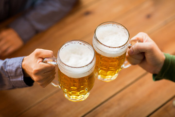 close up of hands with beer mugs at bar or pub