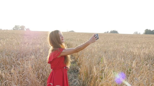 Beautiful woman taking selfie in yellow field