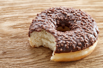 Bitten chocolate donut on a wooden table