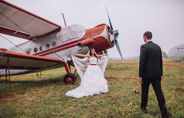 wedding couple at the airport with planes. groom and bride fly to wedding travel by plane. Couple embracing near old airplane