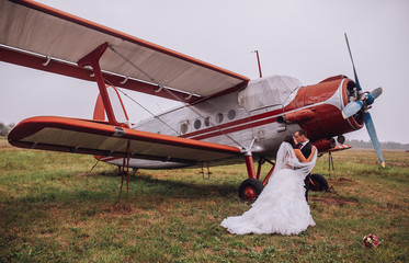 wedding couple at the airport with planes. groom and bride fly to wedding travel by plane. Couple embracing near old airplane