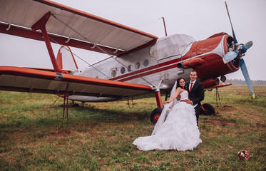wedding couple at the airport with planes. groom and bride fly to wedding travel by plane. Couple embracing near old airplane