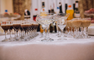 Different alcohol drinks in goblets and wine glasses on wedding buffet table