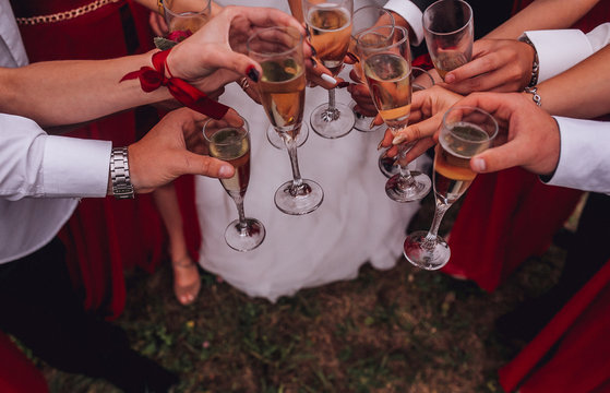 Guests clink glasses on wedding celebration. Lot og glasses with champagne in hand og yung people.