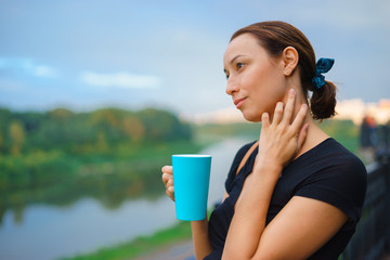 A girl stands outside with cup of tea