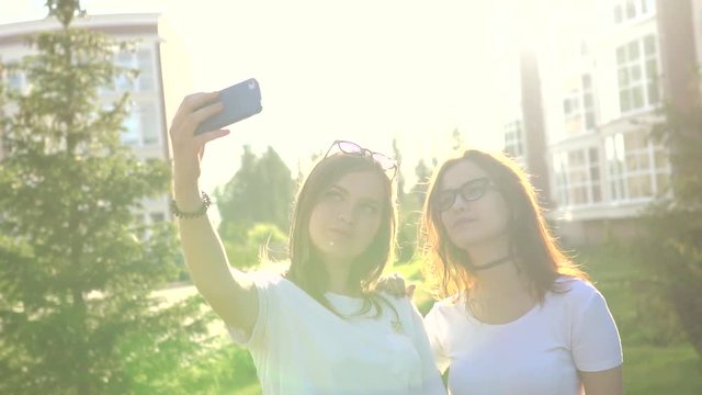 beautiful girls friends taking selfies in the city at sunset with strong back light HD