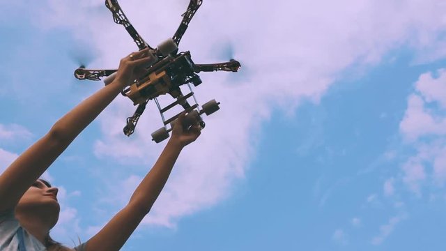 Drone takes off from the hands of a girl near a wind turbine, slow motion.
