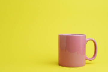 Pink cup of coffee on yellow  background
