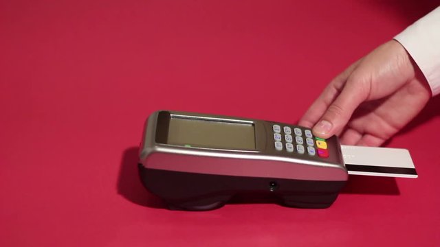 Inserting credit card into card machine and dialing pin code on red background
