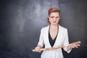 Angry teacher with wooden stick on blackboard