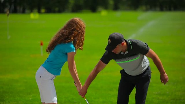 Young man train woman how to hit ball in golf