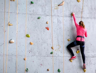 Foto op Plexiglas Beautiful young woman starts to climbing big artificial wall © EdNurg