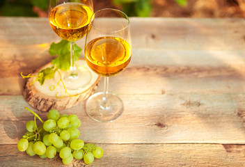 Green grape and two glasses of white wine in the vineyard