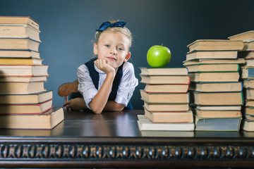 Closeup school girl sitting at the table with many books