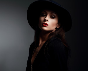 Elegant makeup woman in fashon hat and red lips posing on dark s