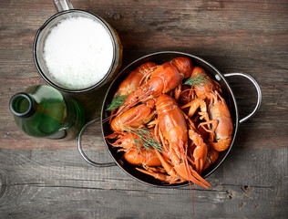 boiled crawfish in a plate and beer on a wooden background
