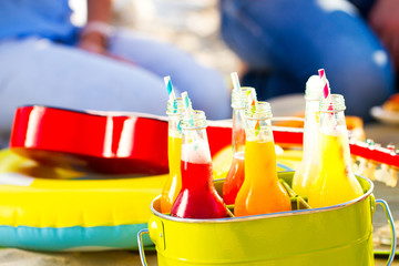 Bottles of lemonade, standing in a colorful green bucket on the