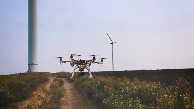 Drone flies near the wind turbine, slow motion.