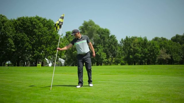 Man brings flagstick and sticks in hole at course
