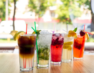glasses of cold fruit cocktaisl with ice, mint and pieces of fruit on a white background