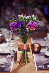 Flowers composition in restaurant, roses and irises, combination shades of purple