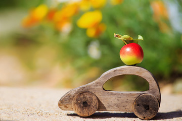 harvesting. wooden toy car with an apple. ripe apple on the car roof. the concept of farmers' delivery of fruits and vegetables. empty space for your text