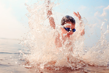 kid dives into the water. splashes of water around a swimmer diving into the water. kid excited...