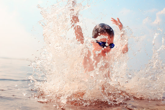 kid dives into the water. splashes of water around a swimmer diving into the water. kid excited about swimming. the concept of a happy childhood