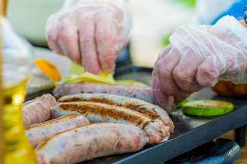 Chef roasting sausages and vegetables on the grill