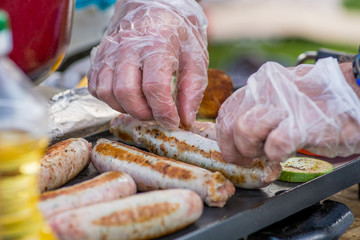 Chef roasting sausages and vegetables on the grill