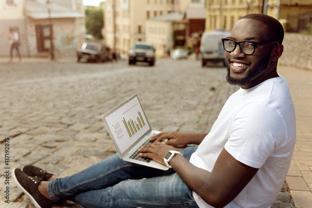 Wall mural Delighted smiling man sitting in the street