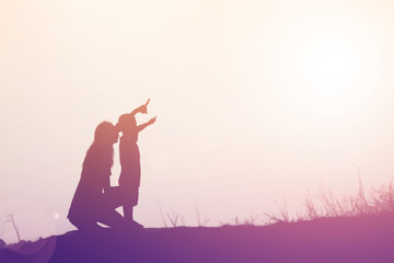 Mother encouraged her son outdoors at sunset, silhouette concept