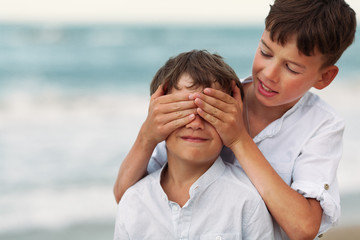 Portrait of happy brothers in white shirts on background of sea