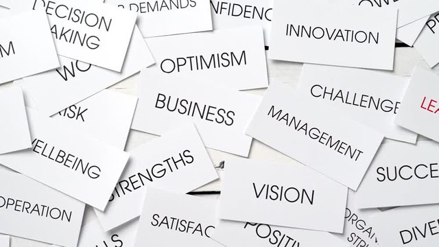 Business related concepts in a tag cloud on cards with one text in red: leadership. Success plan for a company. Dolly shot.