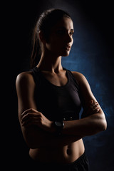 Beautiful sportive girl posing with crossed arms over dark background.