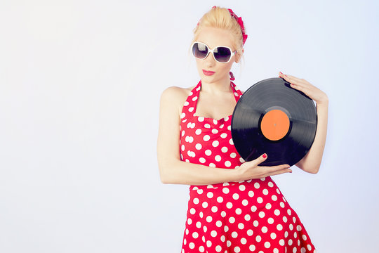 Pin-up girl in vintage dress holding a vinyl record