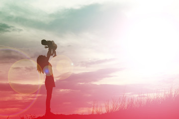 Fototapeta na wymiar Mother holding baby walking on the sunset background.
